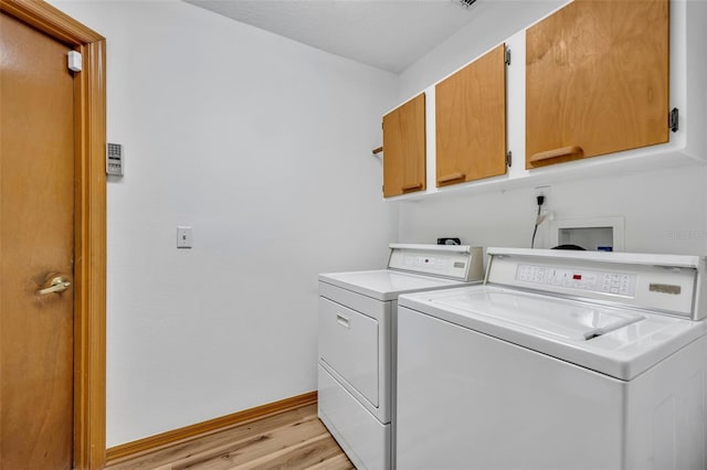 laundry area with cabinets, washer and dryer, and light hardwood / wood-style flooring