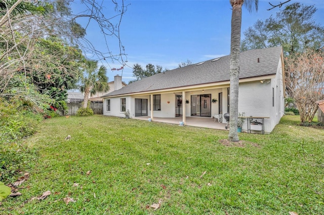 rear view of house featuring a lawn and a patio