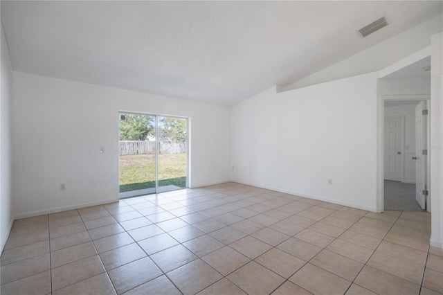 tiled empty room featuring lofted ceiling