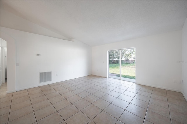 empty room with lofted ceiling and light tile patterned floors