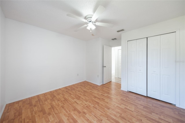 unfurnished bedroom with a textured ceiling, light hardwood / wood-style floors, a closet, and ceiling fan