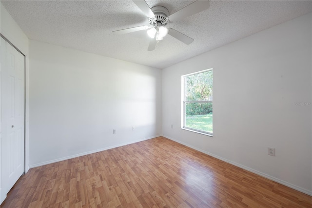 unfurnished bedroom with a textured ceiling, a closet, ceiling fan, and light wood-type flooring