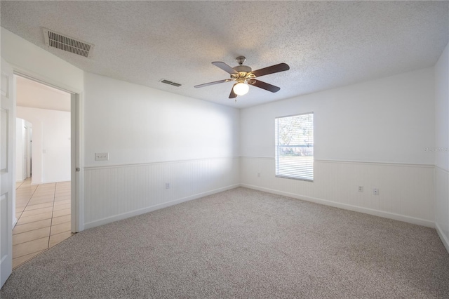 carpeted empty room featuring ceiling fan and a textured ceiling