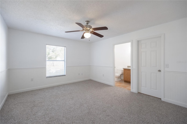 spare room featuring ceiling fan, light colored carpet, and a textured ceiling