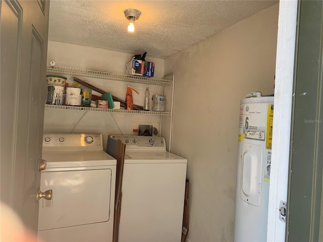 washroom with a textured ceiling, laundry area, washer and clothes dryer, and water heater