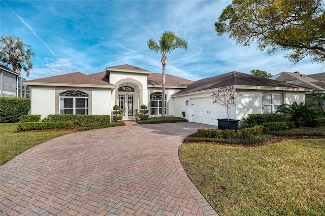 view of front of property featuring a garage, a front yard, and french doors