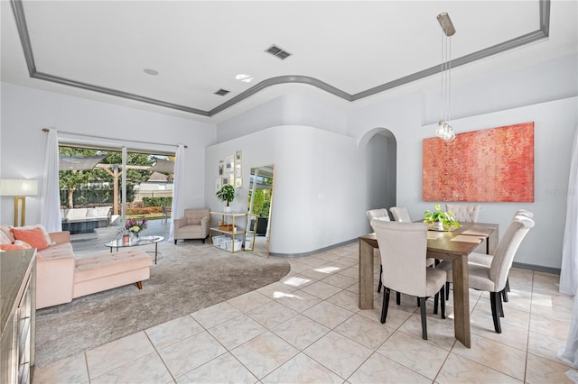 tiled dining space featuring crown molding and a tray ceiling