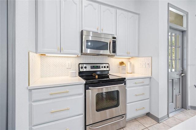 kitchen with white cabinetry, appliances with stainless steel finishes, light tile patterned flooring, and backsplash