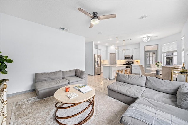 living room featuring sink, light tile patterned floors, and ceiling fan