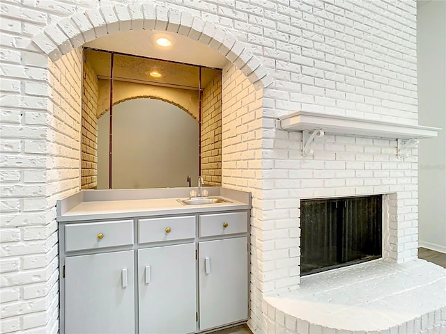 bathroom featuring a fireplace, vanity, and brick wall