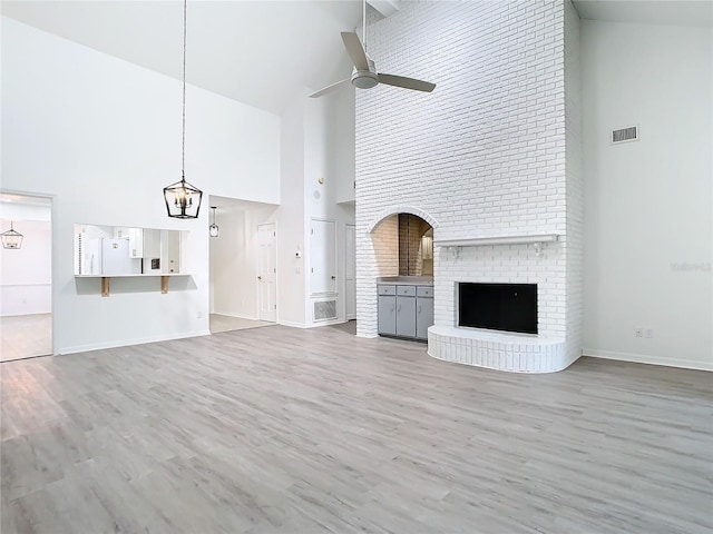 unfurnished living room featuring a fireplace, high vaulted ceiling, and ceiling fan