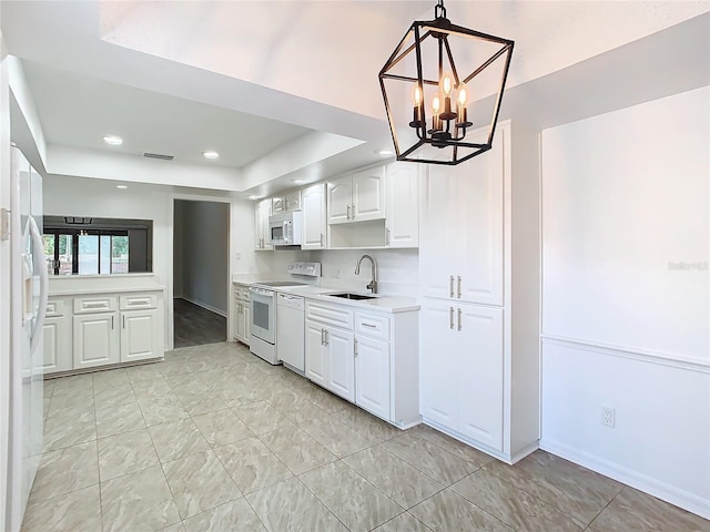 kitchen with sink, a notable chandelier, pendant lighting, white appliances, and white cabinets