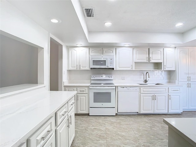 kitchen featuring white appliances, light stone counters, white cabinetry, and sink