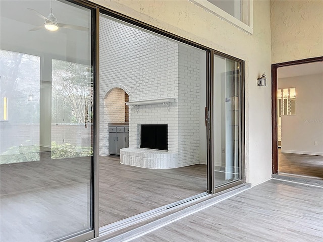 interior space with ceiling fan, wood-type flooring, and a brick fireplace