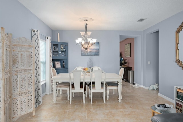 tiled dining room with a textured ceiling, an inviting chandelier, and plenty of natural light