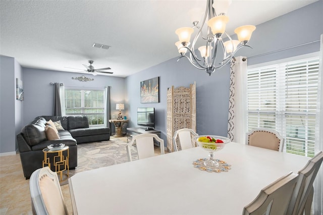 dining area with a textured ceiling and ceiling fan with notable chandelier