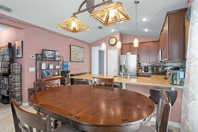 tiled dining area featuring sink and vaulted ceiling