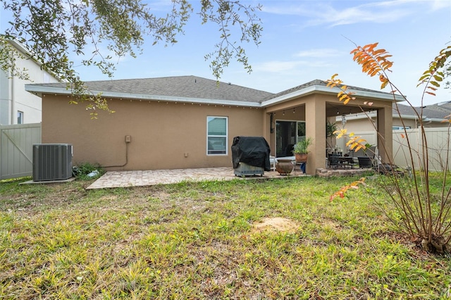 rear view of property featuring a yard, cooling unit, and a patio area