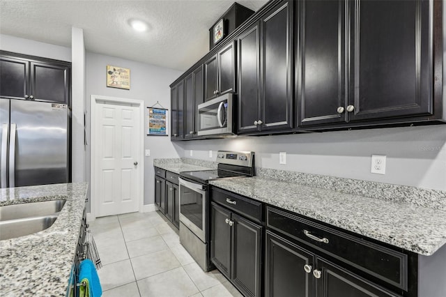 kitchen featuring sink, light tile patterned floors, light stone countertops, a textured ceiling, and stainless steel appliances