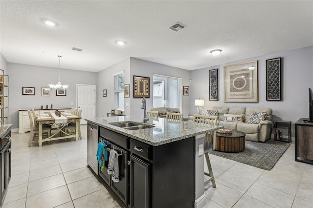 kitchen featuring sink, pendant lighting, a breakfast bar, light stone counters, and a center island with sink