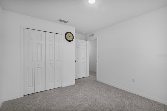 unfurnished bedroom featuring light carpet and a closet