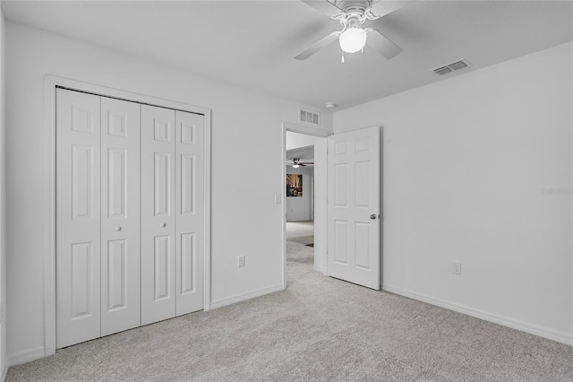 unfurnished bedroom featuring ceiling fan, light colored carpet, and a closet