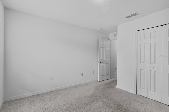 unfurnished bedroom featuring light carpet and a closet