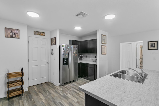 kitchen with hardwood / wood-style floors, stainless steel fridge, kitchen peninsula, and sink