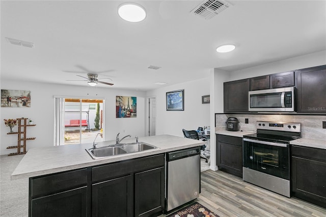 kitchen with ceiling fan, sink, backsplash, light hardwood / wood-style floors, and appliances with stainless steel finishes