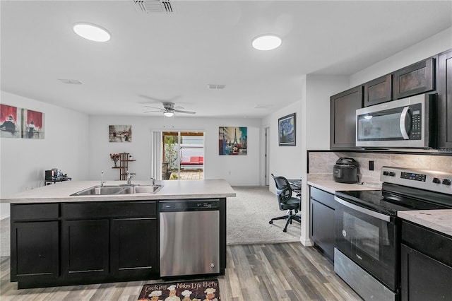 kitchen featuring sink, ceiling fan, tasteful backsplash, wood-type flooring, and stainless steel appliances