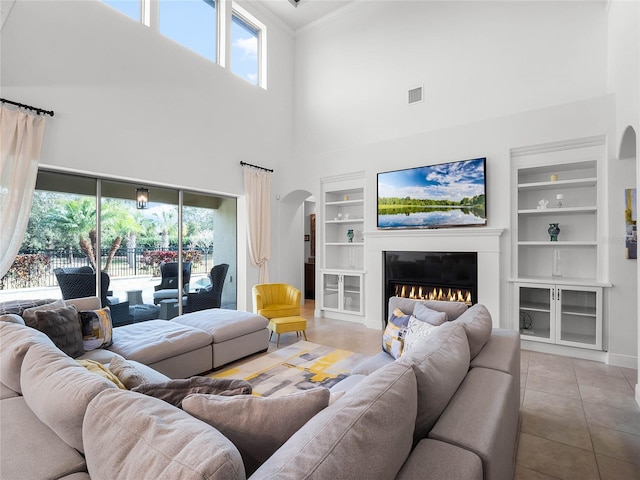 living room with built in shelves, crown molding, and light tile patterned floors