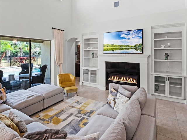 tiled living room featuring a towering ceiling and built in features