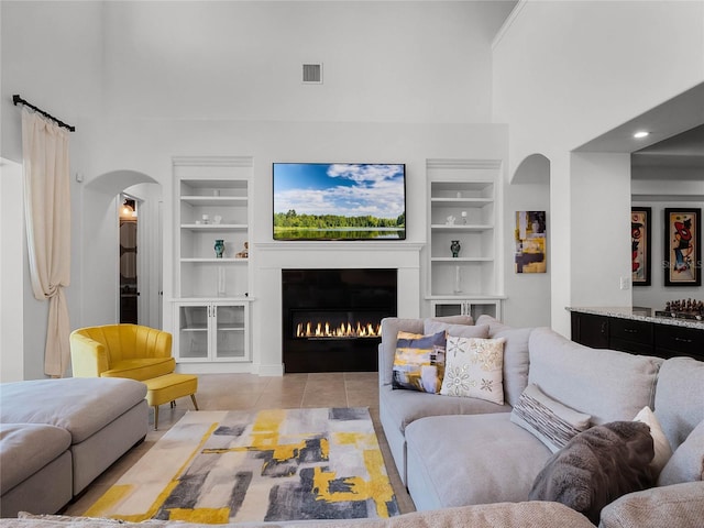 living room featuring built in shelves, light tile patterned flooring, and a high ceiling