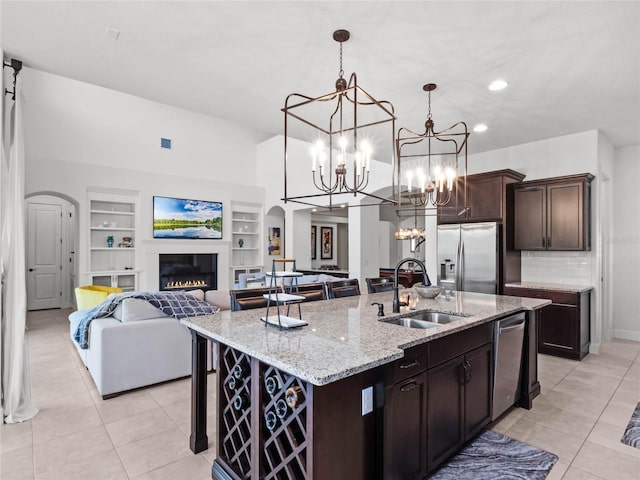 kitchen with pendant lighting, an island with sink, sink, dark brown cabinetry, and stainless steel appliances