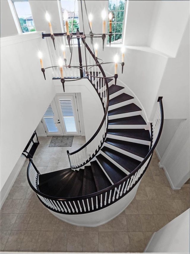 stairs with tile patterned flooring, plenty of natural light, and a chandelier