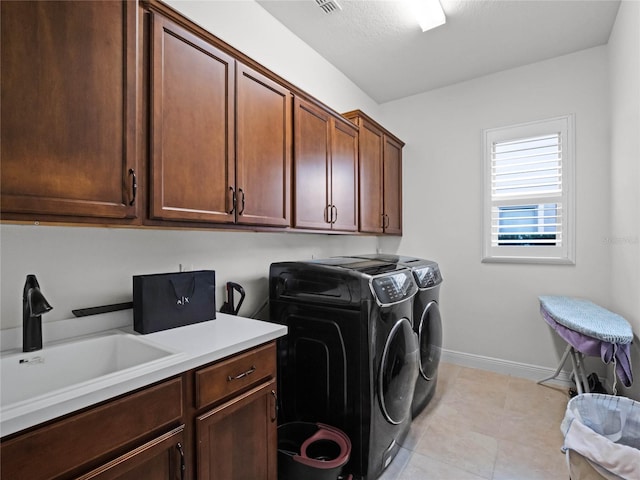 laundry room featuring cabinets, light tile patterned flooring, sink, and washing machine and clothes dryer