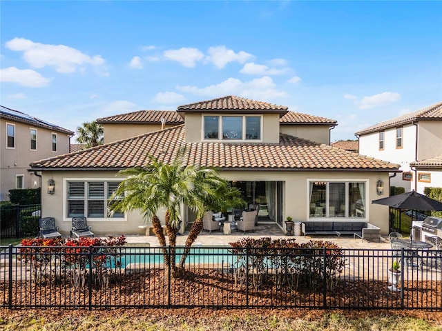 rear view of property featuring a fenced in pool and a patio