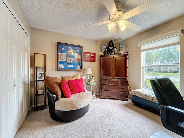 sitting room featuring ceiling fan, a textured ceiling, and carpet flooring