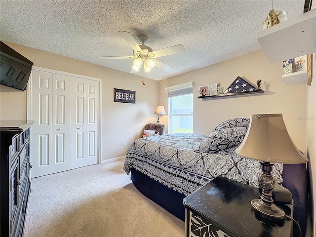 carpeted bedroom with a textured ceiling, ceiling fan, and a closet