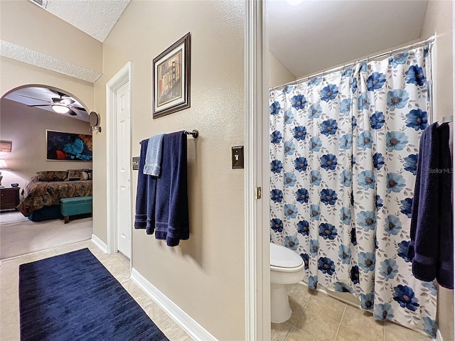 bathroom featuring toilet, a shower with shower curtain, ceiling fan, tile patterned floors, and a textured ceiling