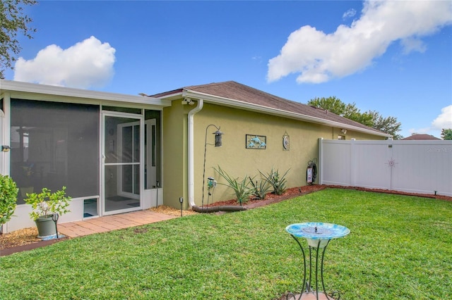 back of property with a sunroom and a lawn