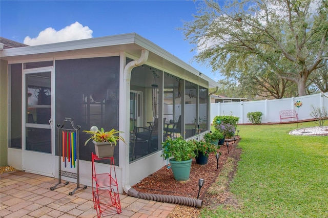 view of home's exterior with a sunroom and a lawn