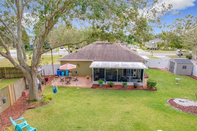 rear view of house featuring a sunroom, a shed, a yard, and a patio