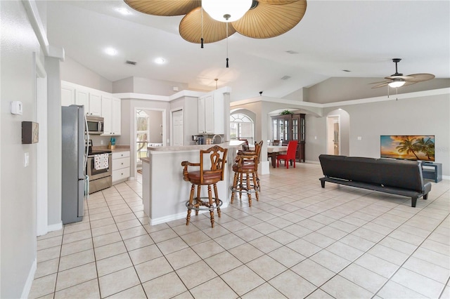 kitchen featuring lofted ceiling, ceiling fan, light tile patterned floors, appliances with stainless steel finishes, and white cabinetry