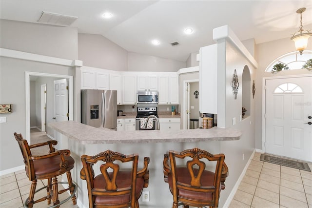 kitchen with appliances with stainless steel finishes, decorative light fixtures, white cabinetry, and light tile patterned flooring