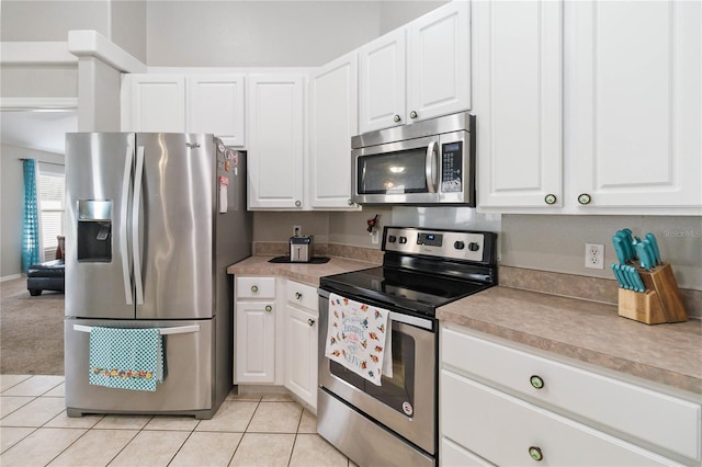 kitchen with white cabinets, light tile patterned floors, and stainless steel appliances