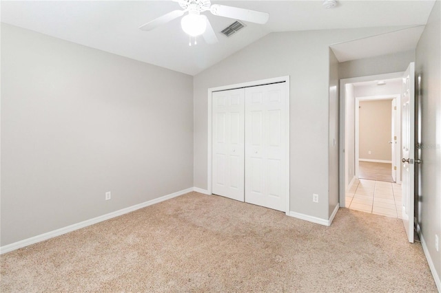 unfurnished bedroom with ceiling fan, vaulted ceiling, light colored carpet, and a closet