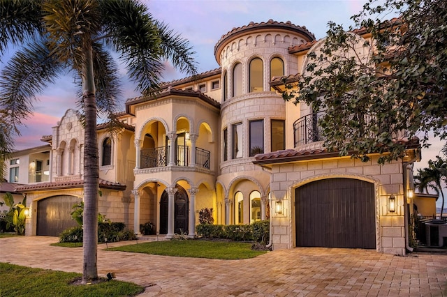 mediterranean / spanish-style house featuring a tiled roof, cooling unit, decorative driveway, and a balcony