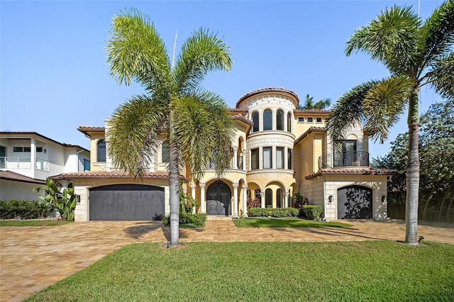 mediterranean / spanish house featuring a garage, a front lawn, decorative driveway, and a balcony