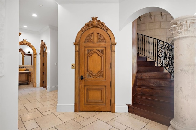 interior space featuring baseboards, arched walkways, crown molding, stone tile flooring, and recessed lighting